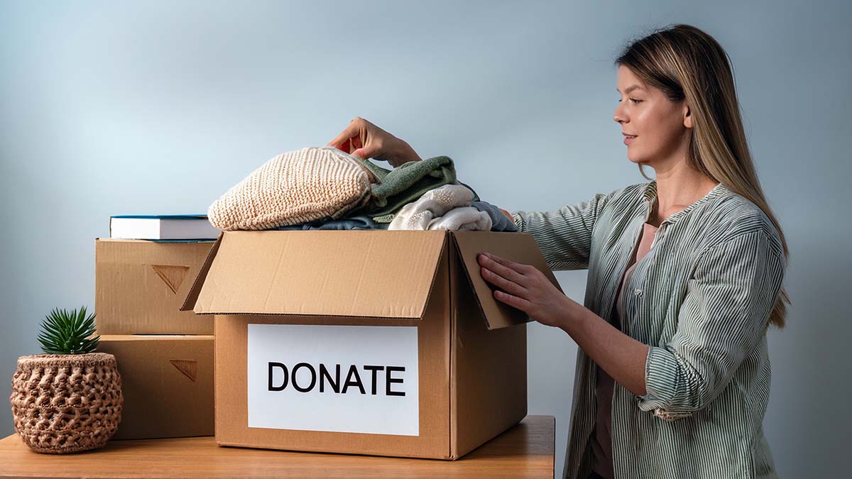 Woman Placing Household Items In Donation Box