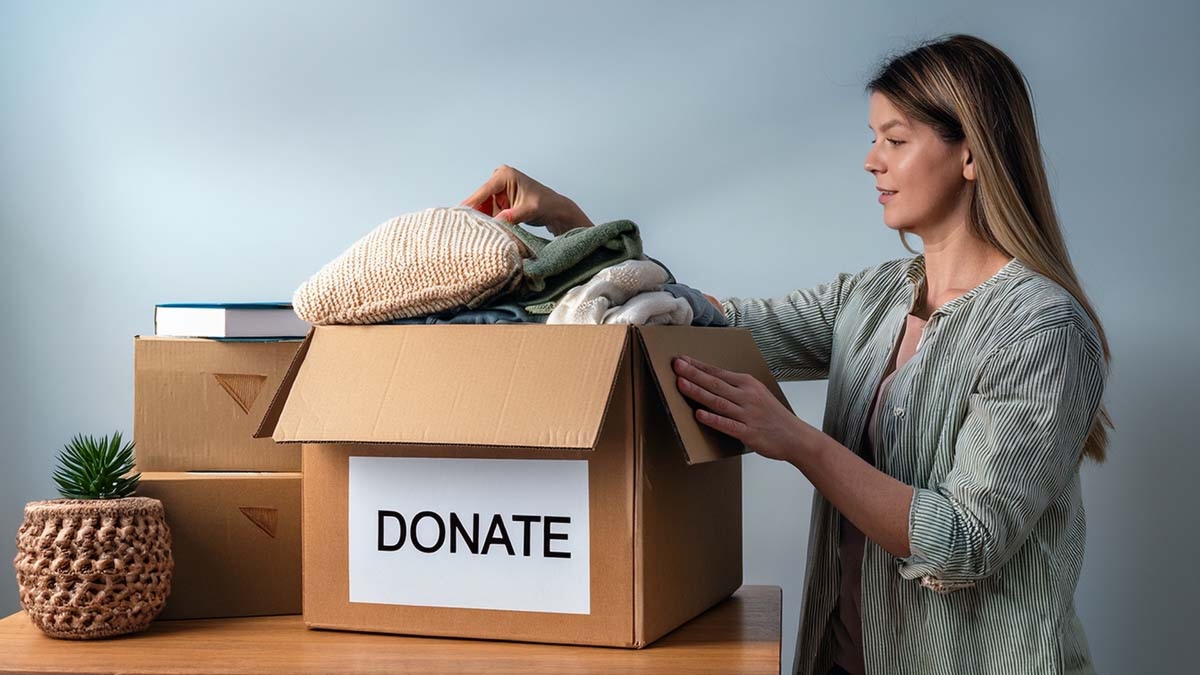 Woman Placing Household Items In Donation Box
